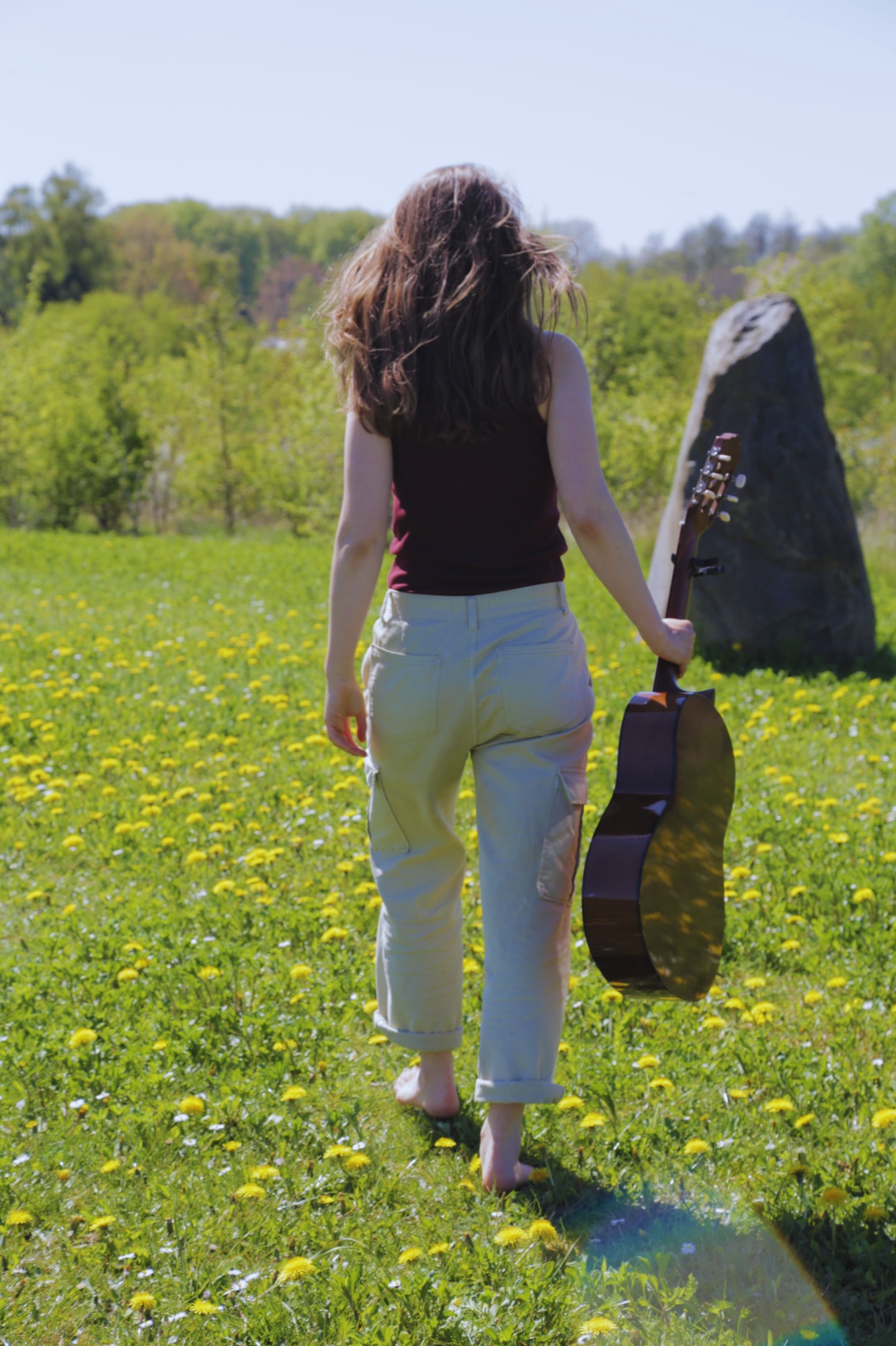 Emma walking into a field with her guitar